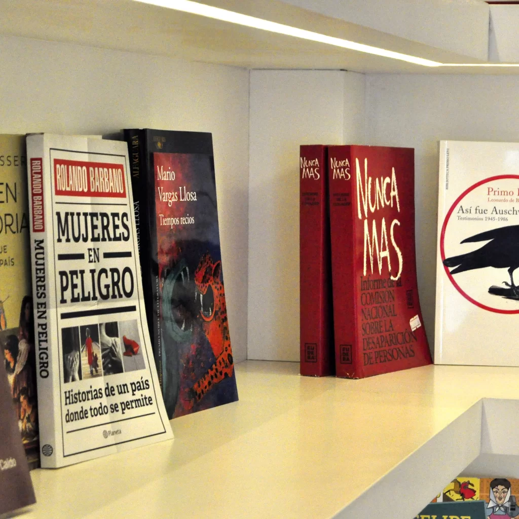 Estantería con varios libros, incluyendo un ejemplar de 'Mujeres en Peligro' de Rolando Barbano.